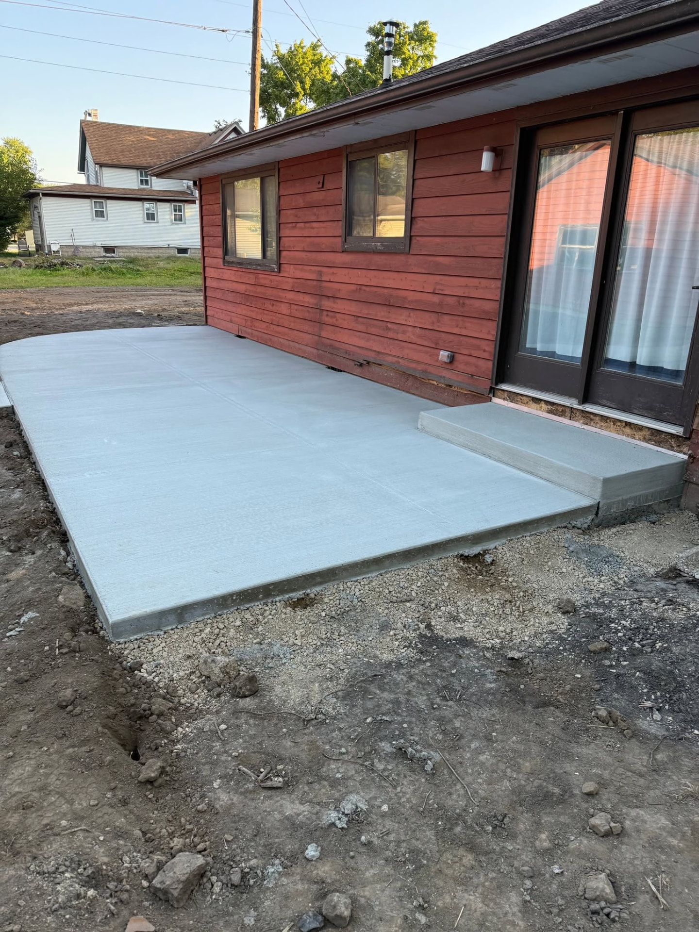 New broom-finished concrete patio with a poured step at a sliding patio door